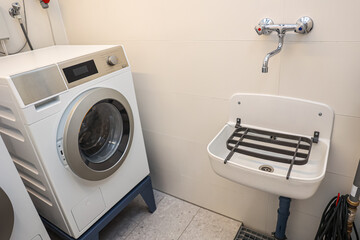 Modern washing machine and sink in laundry room