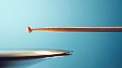 Close-up of drumstick poised near drum surface