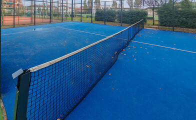 outdoor padel court with a blue surface, equipped with net floodlights and glass © manola72