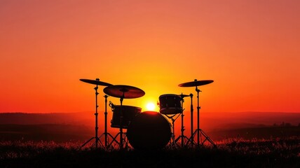 Naklejka premium Silhouetted drum set against vibrant sunset in serene landscape