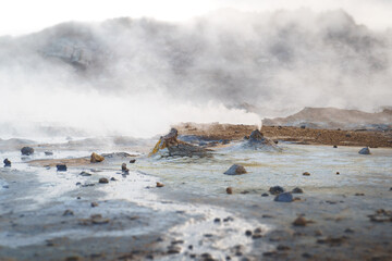 Sulfuric steam vents in the Hverir geothermal area of Námafjall, Iceland, emitting clouds of vapor on a barren landscape.