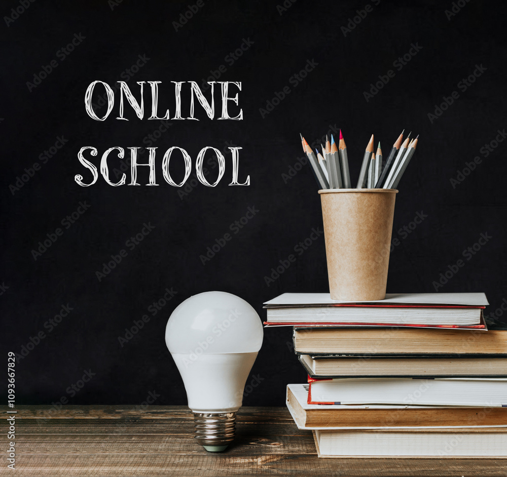 Poster a stack of books and a light bulb on a table with the words online school written above them