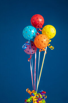 Colorful Pickleball balloons  on a blue background with ribbons-  group with Red, Blue, Yellow, Orange and Purple Pickleball Balloons.