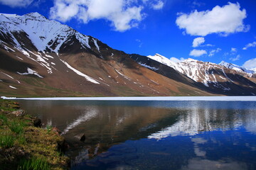 Fototapeta premium Reflection of clouds and waves in the calm water of a half frozen lake