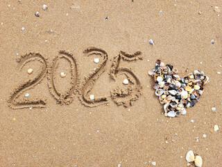 Numbers written in the sand next to a pile of shells in the shape of hearts. New Year 's Eve 2025.