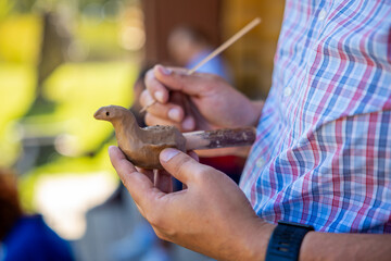 Person Crafting Clay Bird Sculpture Outdoors in Plaid Shirt
