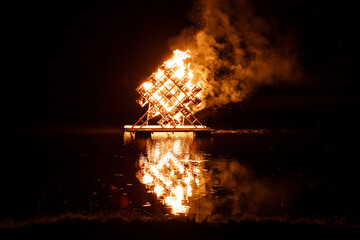 Geometric Structure Ablaze on Floating Platform at Night