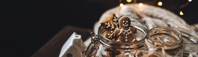 Banner. Big glass jar with homemade gingerbread cookies for Santa Claus. Idea for handmade present, gift for family and friends. Cozy atmosphere, simple festive home decor with candles, fairy lights