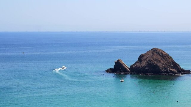 Snoopy Island in Fujairah, UAE, viewed from the coast with clear blue waters surrounding the rocky island