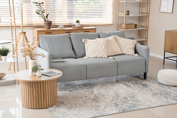 Interior of stylish living room with grey sofa and coffee table near window