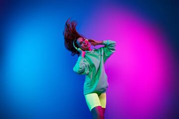 Photo of shiny carefree lady dressed green sweatshirt earphones enjoying music dancing empty space isolated blue light color background