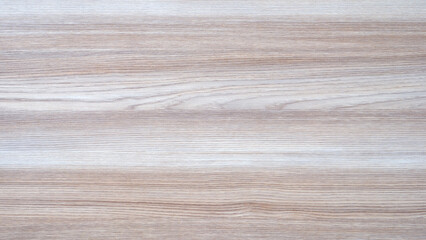 A wooden surface with a grain pattern. The grain is visible in the wood. The surface is light in color