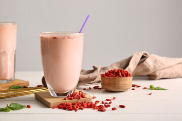 Glasses of fresh goji berry smoothie with mint on white wooden table