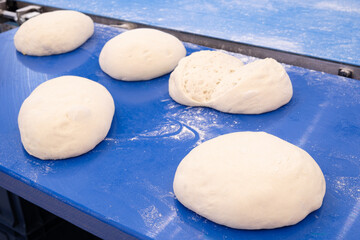 A blue counter with five loaves of bread on it. The bread is sliced and ready to be served