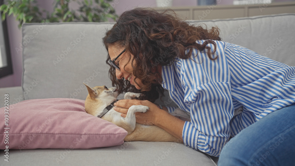 Sticker A middle-aged hispanic woman enjoys bonding with her chihuahua on a couch in a cozy living room setting.