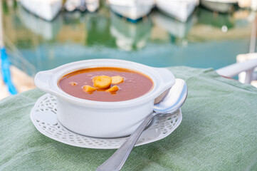 Homemade tasty fish or bisque soup with croutons and view on yacht boats and houses of Port...