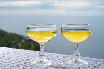 Cold sparkling wine, cava or champagne in two coupe glasses on table with sea water view