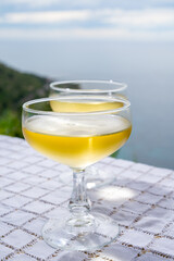 Cold sparkling wine, cava or champagne in two coupe glasses on table with sea water view