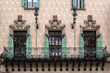 Balcony with cast iron rail, three rectangular windows with open green shutters and moldings. From the Peace Window Series.