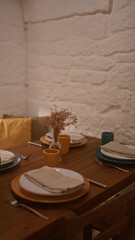 A cozy italian restaurant indoors with a rustic table setting, featuring plates, cups, cutlery, and a vase of flowers, creating an inviting atmosphere for a warm dining experience.