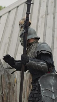 Dark knight sneaks into settlement to fight village residents. Evil warrior prepares to attack local people. Medieval battles closeup on blurred background
