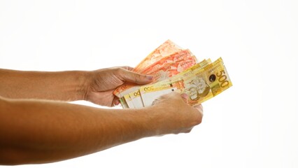 Hands holding philippine peso banknotes over an isolated white background.