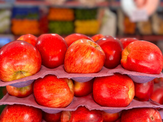 closeup of fresh red apples with green grocery store in background