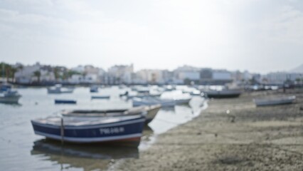 Fototapeta premium Blurred boats floating on the water with a defocused cityscape background in lanzarote, spain.