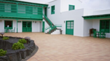 Blurred colonial mexican-style courtyard in lanzarote with green doors, white walls, and defocused...