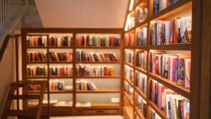 Blurred background of a defocused library setting with bookshelves filled with books under warm lighting