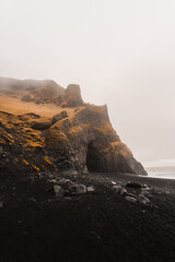 Basalt columns and black sand beach create a dramatic landscape on the southern coast of iceland,...
