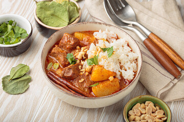 Aromatic massaman curry, a staple of thai cuisine, served with fragrant rice, tender beef, potatoes, peanuts. Vibrant and flavorful classic dish of Thailand