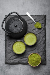 Traditional japanese matcha tea ceremony set on a dark slate plate, including a black iron teapot,...