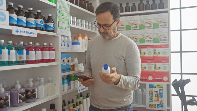 Hispanic man browsing medication in a pharmacy while using smartphone