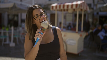 A beautiful young hispanic woman enjoys an ice cream in the charming old town streets of puglia, italy, surrounded by european ambiance.