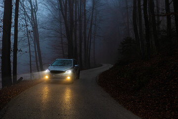 Car driving on mountain road on foggy evening