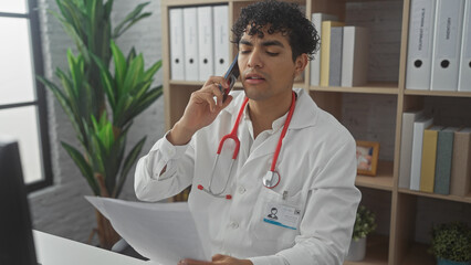 Young hispanic male doctor talking on phone in office