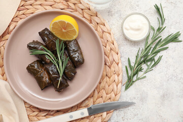 Plate with tasty Dolmas (stuffed grape leaves), sour cream and rosemary on light background