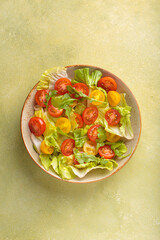 Fresh and vibrant mixed salad with crisp lettuce, juicy red and yellow cherry tomatoes and arugula. Served in a bowl with cutlery on the side. Vitamins and healthy eating habits