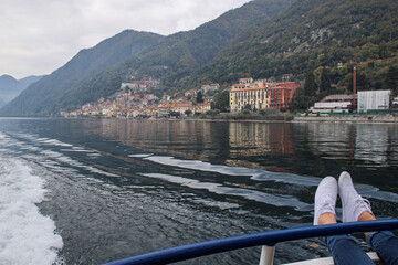 A person relaxes on a boat, enjoying the serene lake and picturesque view of colorful hillside...