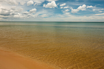 Obraz premium Soft, wispy clouds float over the calm waters of Lake Michigan off the beach at Harrington Beach State Park, Belgium, Wisconsin in late June
