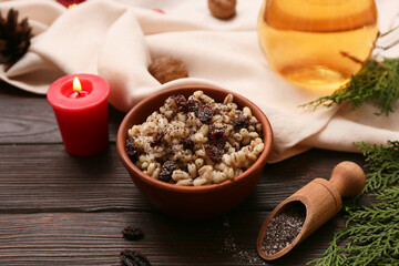Bowl of traditional Ukrainian Kutya dish with coniferous branches and burning candle on wooden background