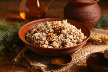 Bowl of traditional Ukrainian Kutya dish with sweet honey and fir branches on wooden background, closeup