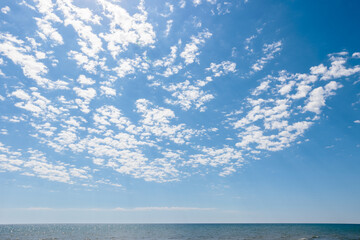 Obraz premium With a backdrop of blue sky, the fluffy clouds drift over a calm Lake Michigan on a morning in early June off the beach at Harrington Beach State Park, Belgium, Wisconsin