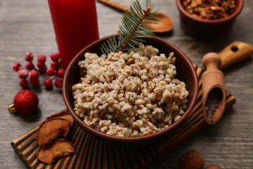 Bowl of traditional Ukrainian Kutya dish with fir branch and Christmas ball on wooden background, closeup