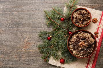Bowls of traditional Ukrainian Kutya dish with almond nuts and Christmas tree branches on wooden background