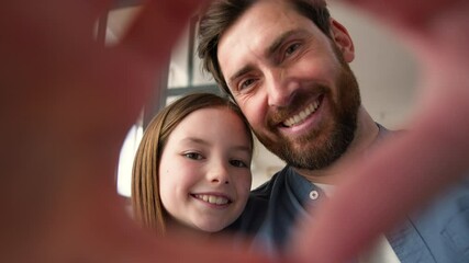 Happy Caucasian family smiling daughter little child carefree dad man guy showing heart love gesture with hands together adorable symbol at home kid girl male father looking at camera trust parenting