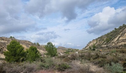 Typisch spanische Landschaft mit sanften Hügeln, etwas grünem Bewuchs und einem dramatischen Wolkenhimmel.