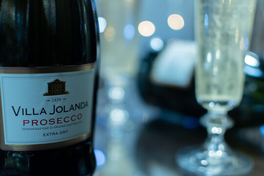 Bottle of Italian white sparkling wine Villa Jolanda Prosecco Extra Dry and flute glasses on blurred festive background with colorful lights. Ukraine, Zhytomyr, November 21, 2024