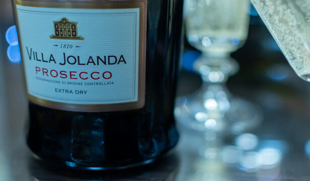 Bottle of Italian white sparkling wine Villa Jolanda Prosecco Extra Dry and flute glasses on blurred festive background with colorful lights. Ukraine, Zhytomyr, November 21, 2024